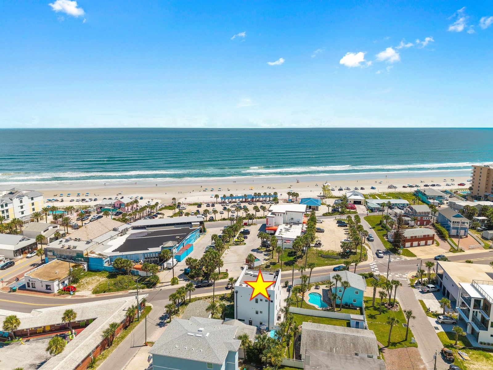 Aerial view of the neighborhood with the home marked and the ocean beyond