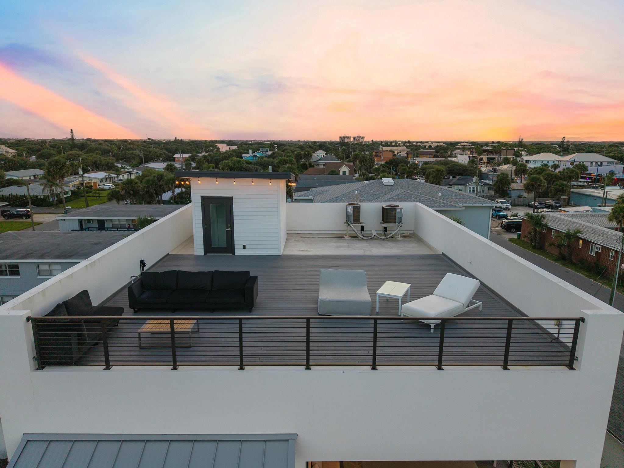 Private rooftop deck at dusk with lounge seating, looking toward the Atlantic
